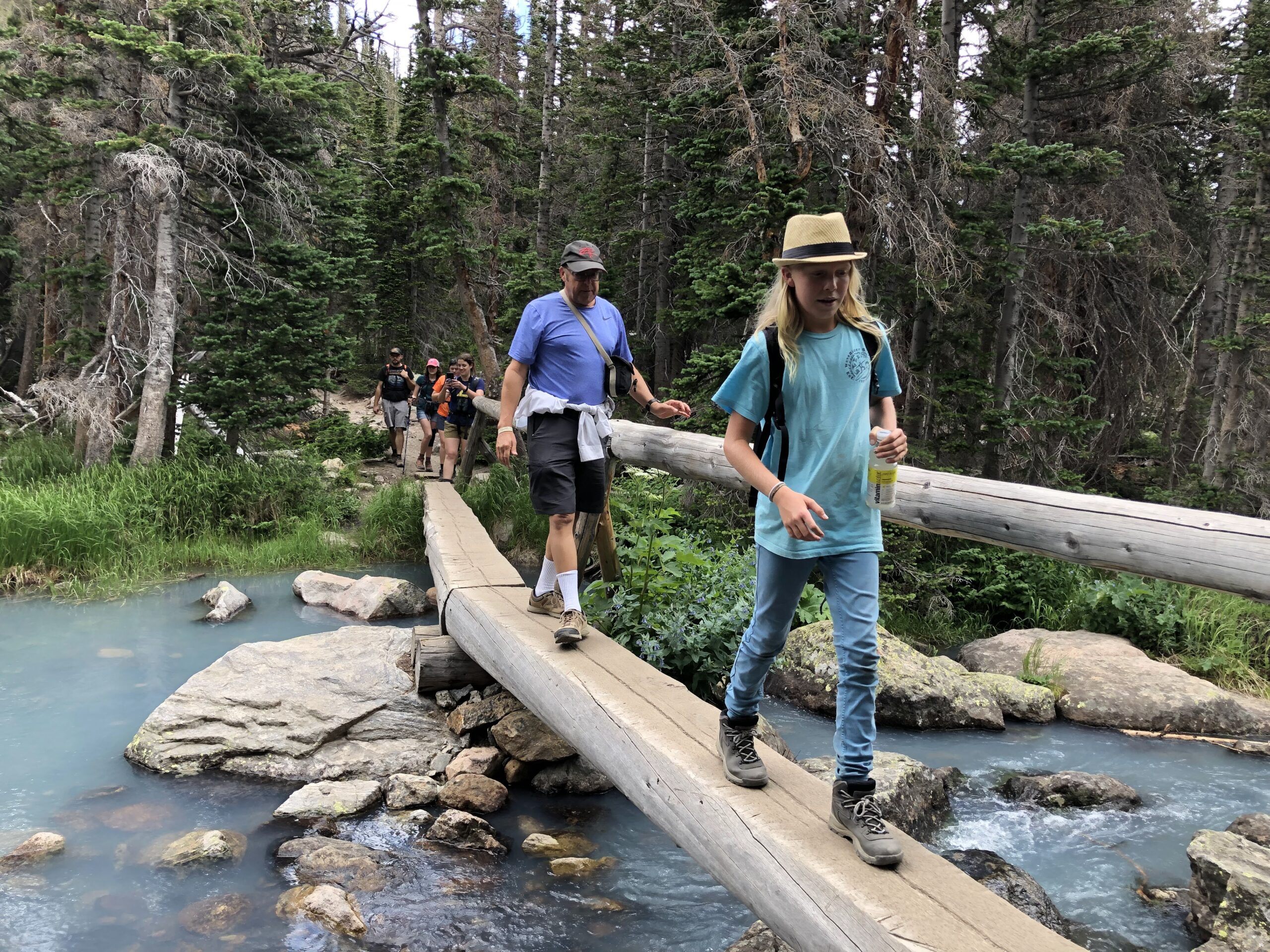 child and adult walking on a bridge over a creek